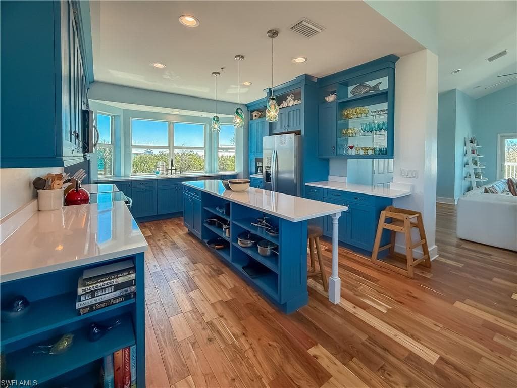 Kitchen featuring open shelves, blue cabinets, visible vents, and stainless steel appliances