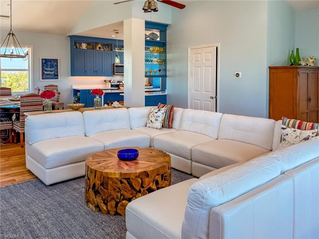 Living area with ceiling fan with notable chandelier and light wood-type flooring