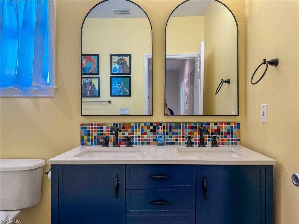 Bathroom featuring decorative backsplash, double vanity, and a sink