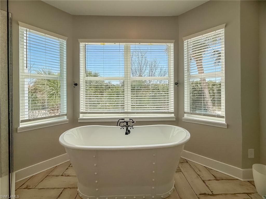 Full bathroom with plenty of natural light, baseboards, and a freestanding tub