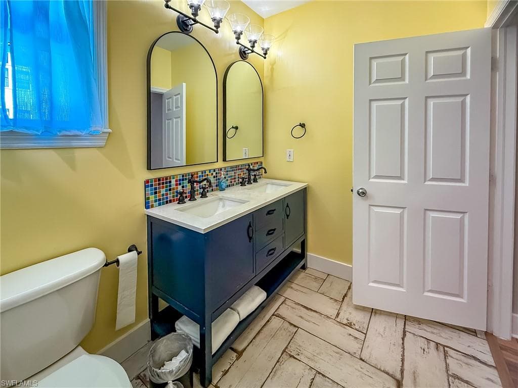 Bathroom with a sink, tasteful backsplash, double vanity, and toilet