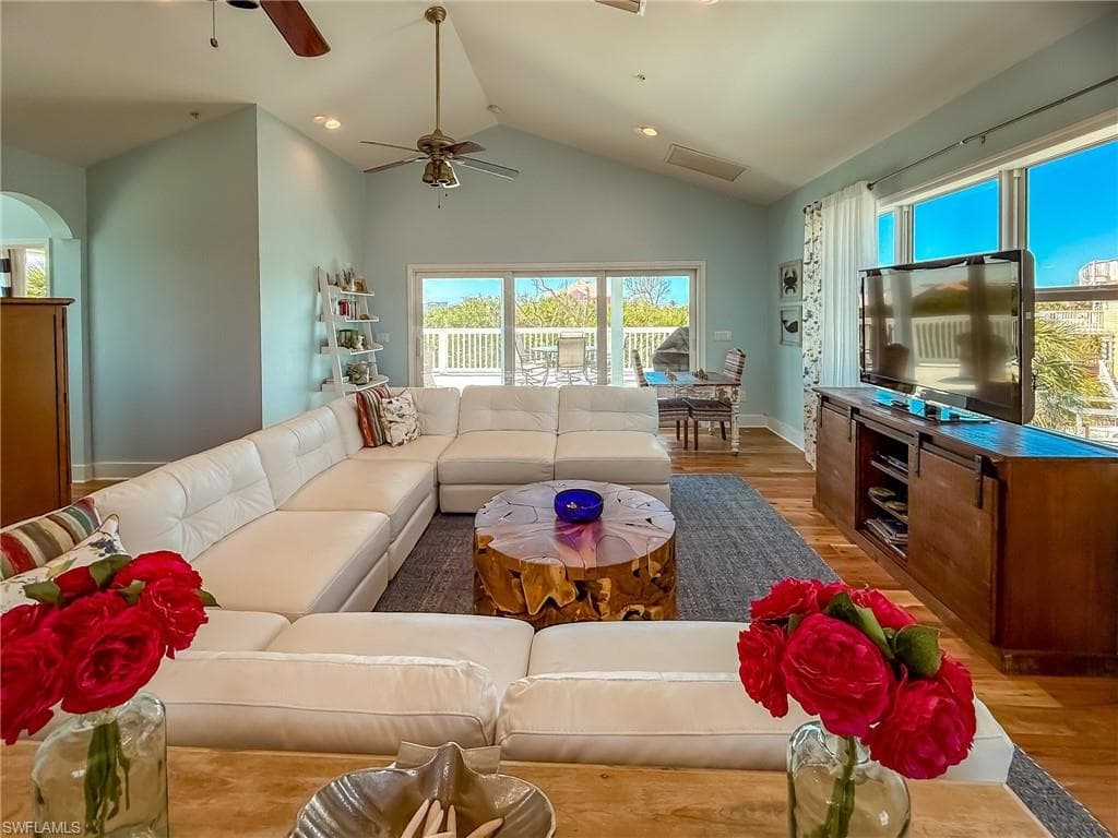 Living room featuring high vaulted ceiling, light wood-style flooring, recessed lighting, arched walkways, and baseboards