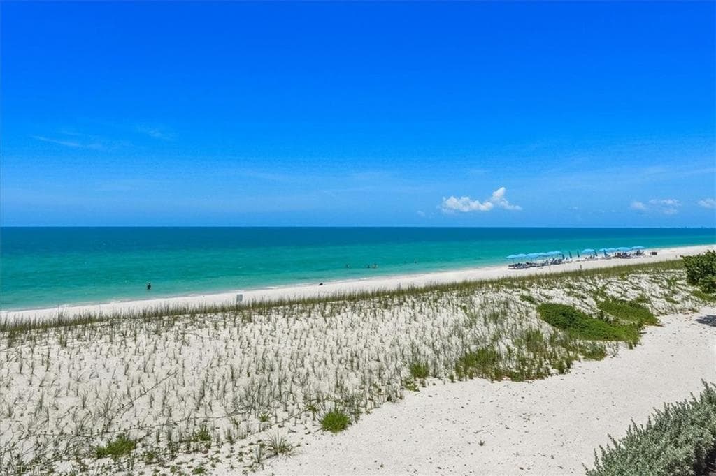 Stunning coastal landscape featuring a wide expanse of white sand beach with gentle waves