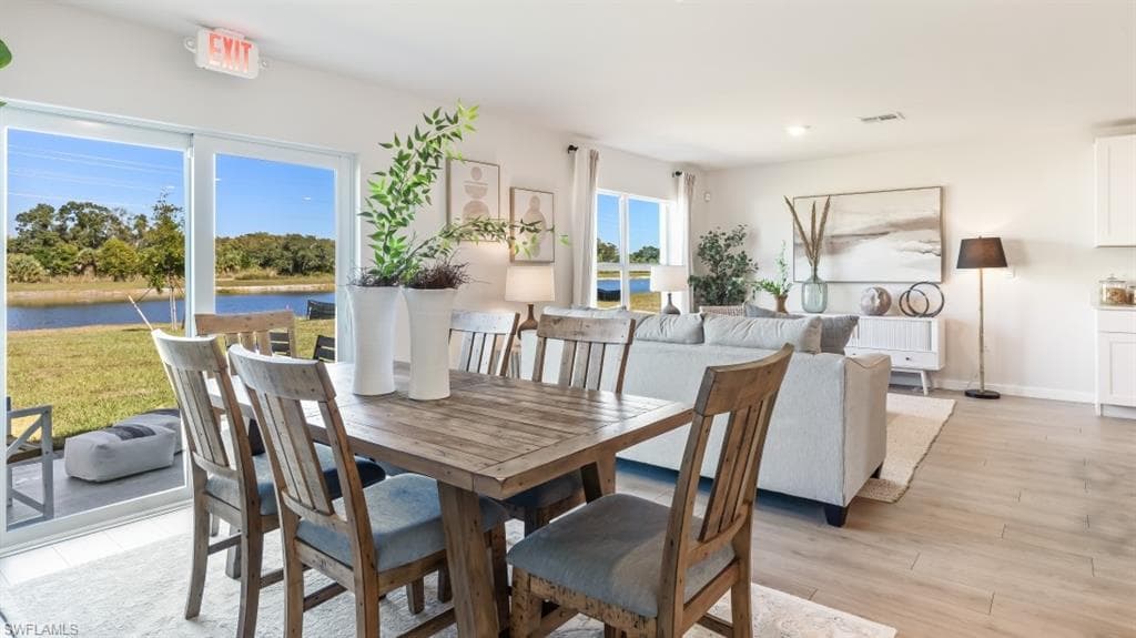 MODEL PHOTO - Dining room with light wood finished floors and a water view