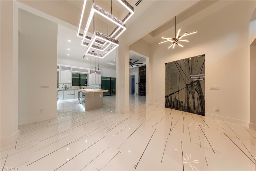 Unfurnished living room with a chandelier, recessed lighting, ceiling fan, and a towering ceiling