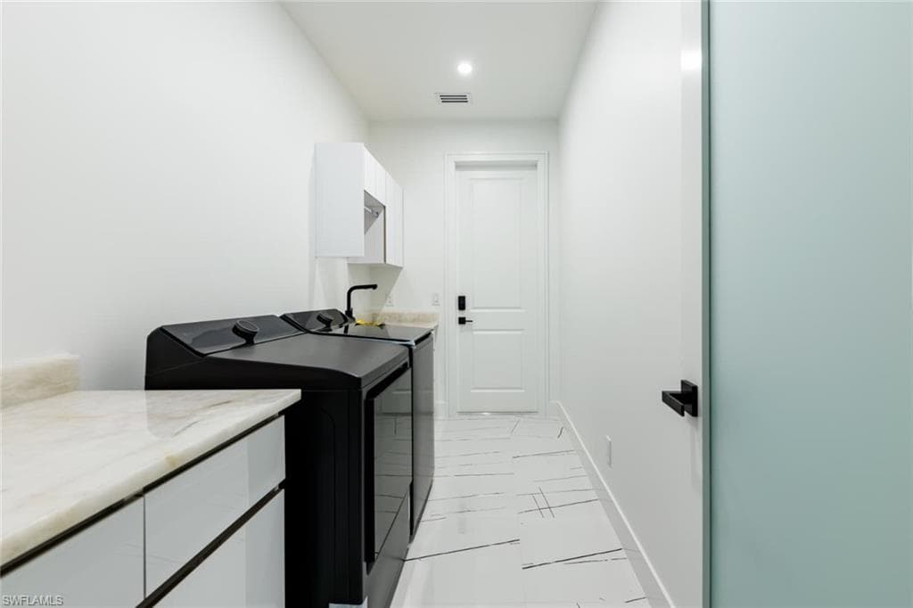 Washroom with cabinet space and washing machine and clothes dryer