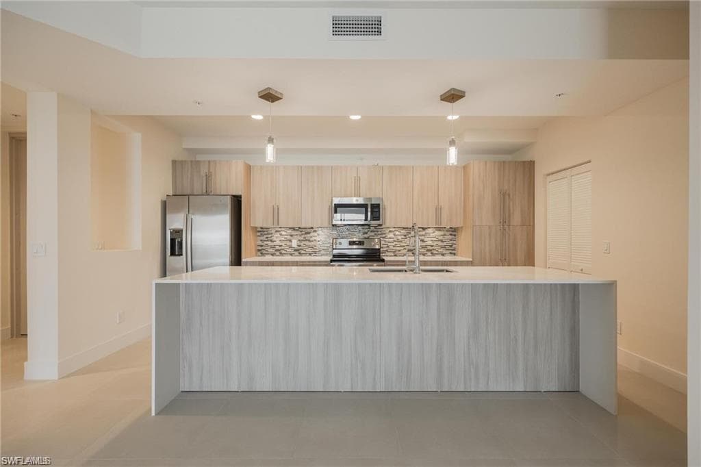 Kitchen featuring baseboards, stainless steel appliances, visible vents, and a sink