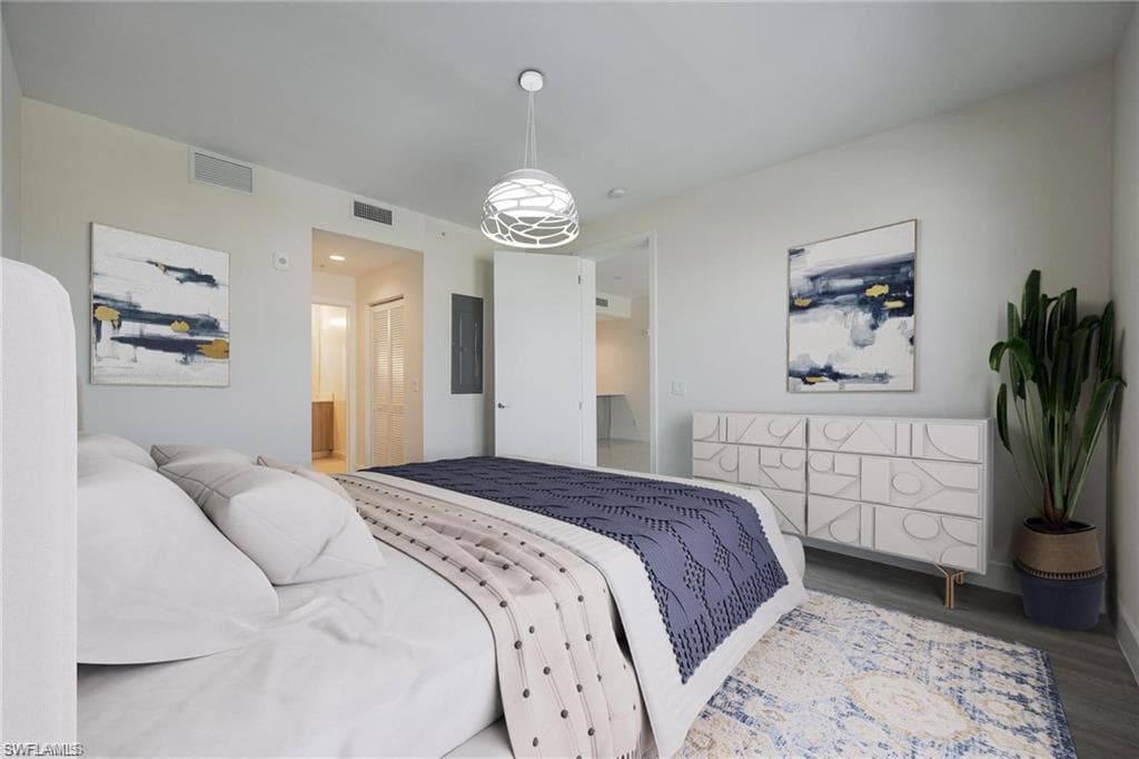 Bedroom with ensuite bath, wood finished floors, visible vents, and baseboards