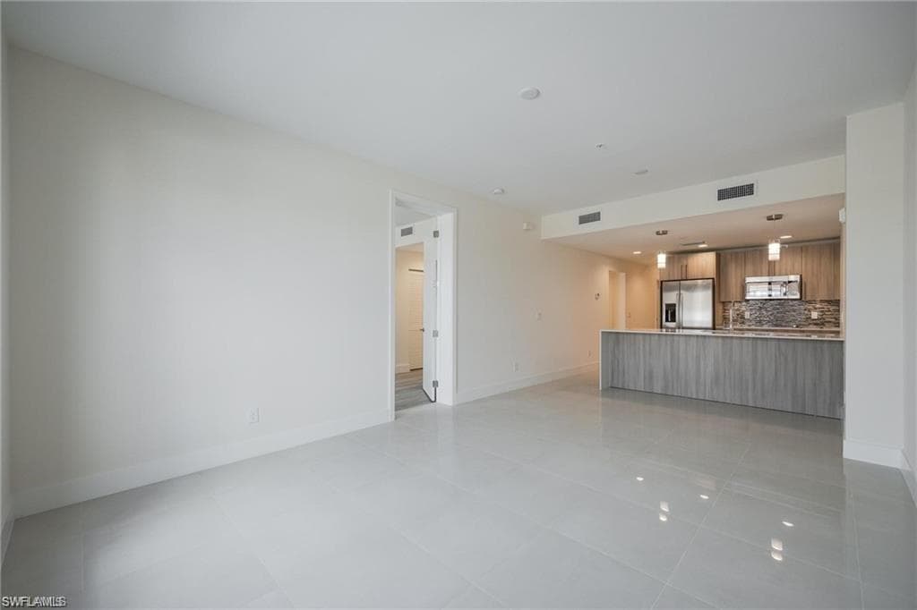 Unfurnished living room featuring baseboards, light tile patterned flooring, and visible vents