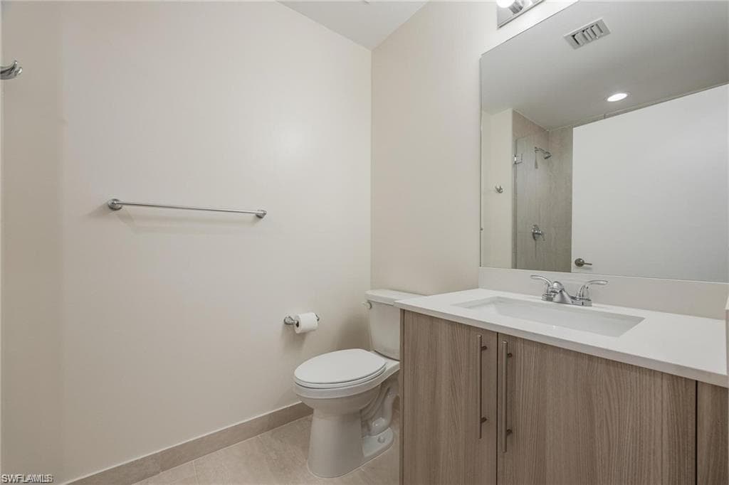 Bathroom with vanity, a shower, baseboards, toilet, and visible vents