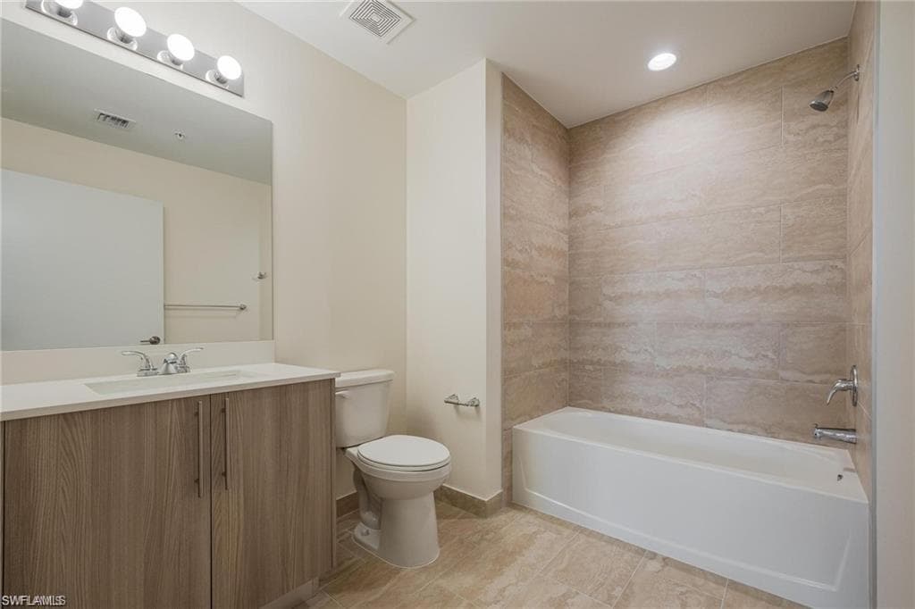 Full bathroom with bathing tub / shower combination, visible vents, vanity, and toilet