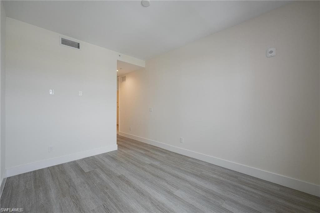 Empty room with baseboards, wood finished floors, and visible vents