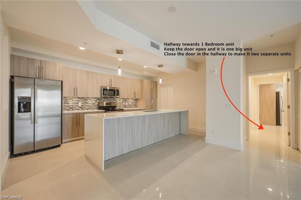 Kitchen with light countertops, visible vents, modern cabinets, decorative backsplash, and appliances with stainless steel finishes