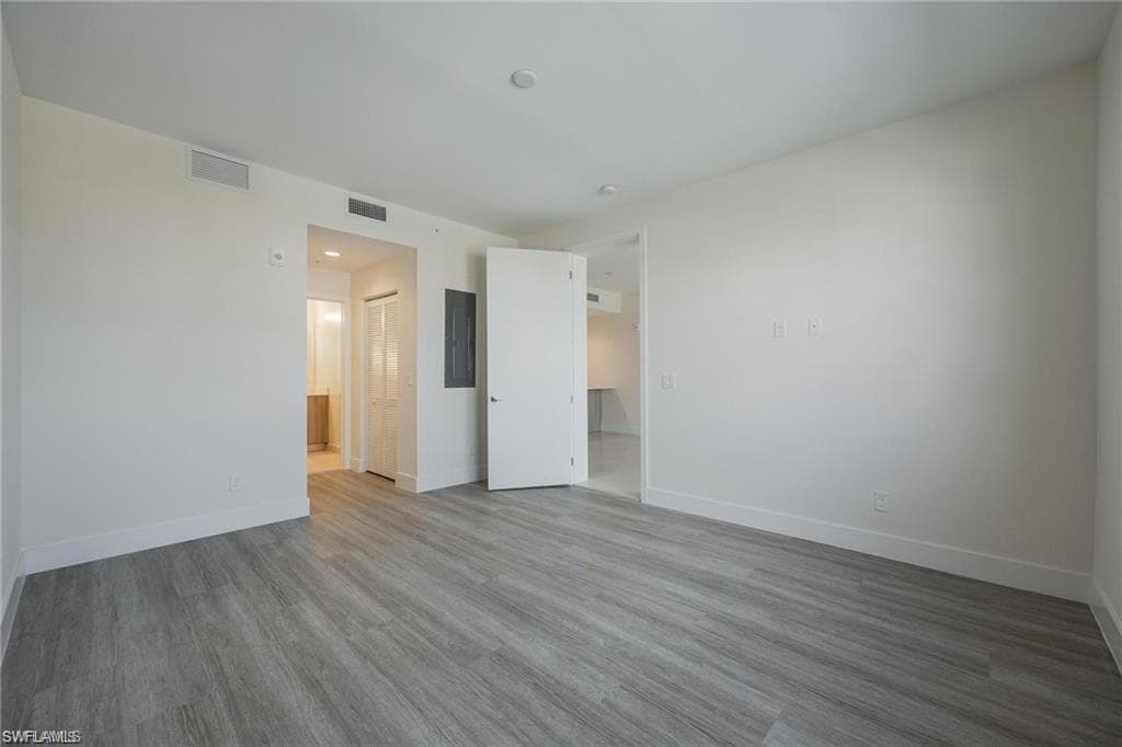 Spare room with baseboards, wood finished floors, and visible vents