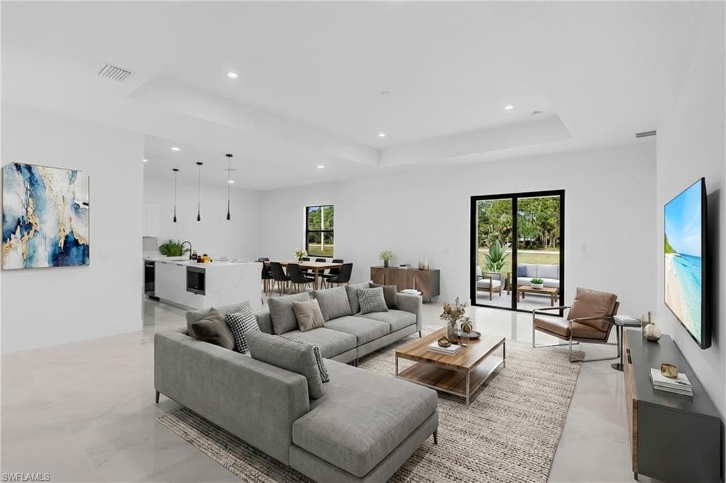 Virtually Staged. Open-concept living space featuring a tray ceiling, recessed lighting, tile flooring, and sliding glass doors to the exterior