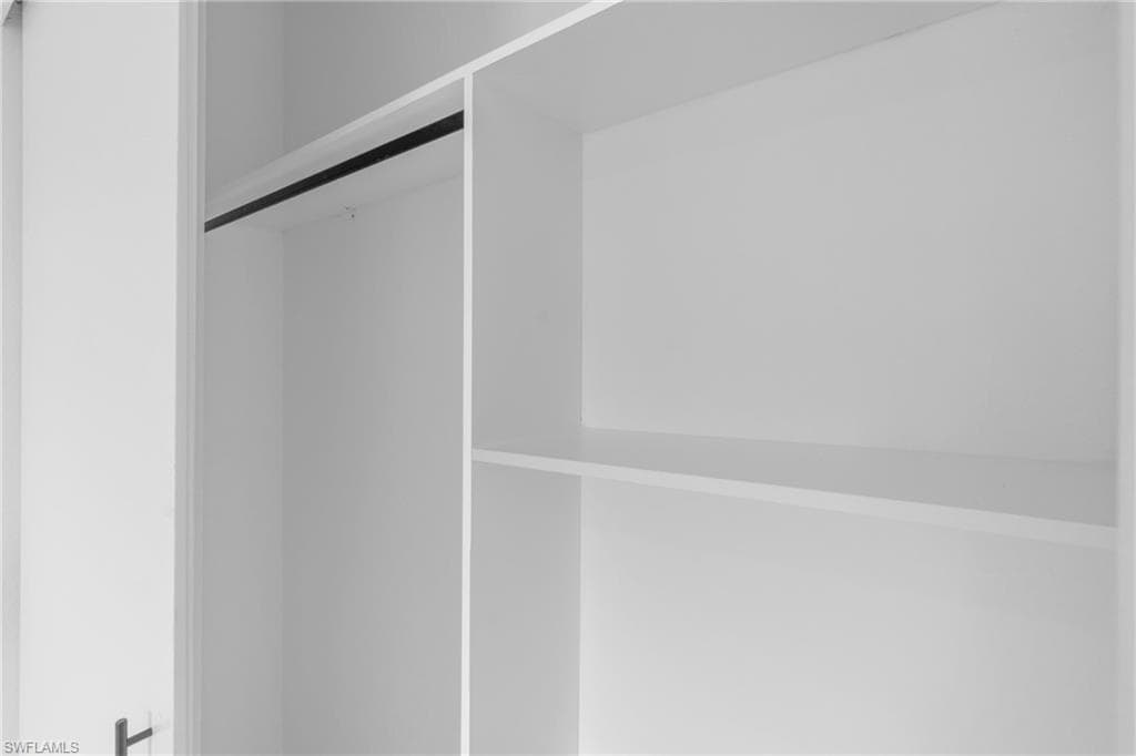 Built-in closet system featuring white shelving, hanging rod, and white paneling