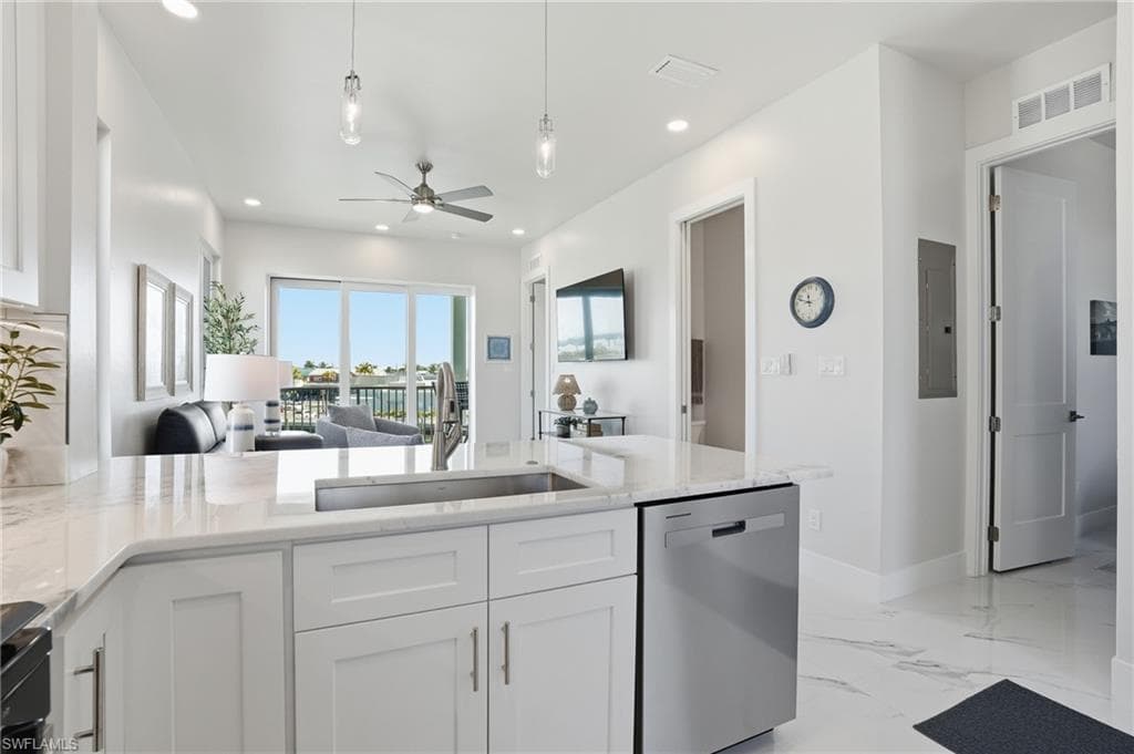 Kitchen with open floor plan, stainless steel dishwasher, white cabinetry, light stone counters, and recessed lighting - Virtually Edited Image
