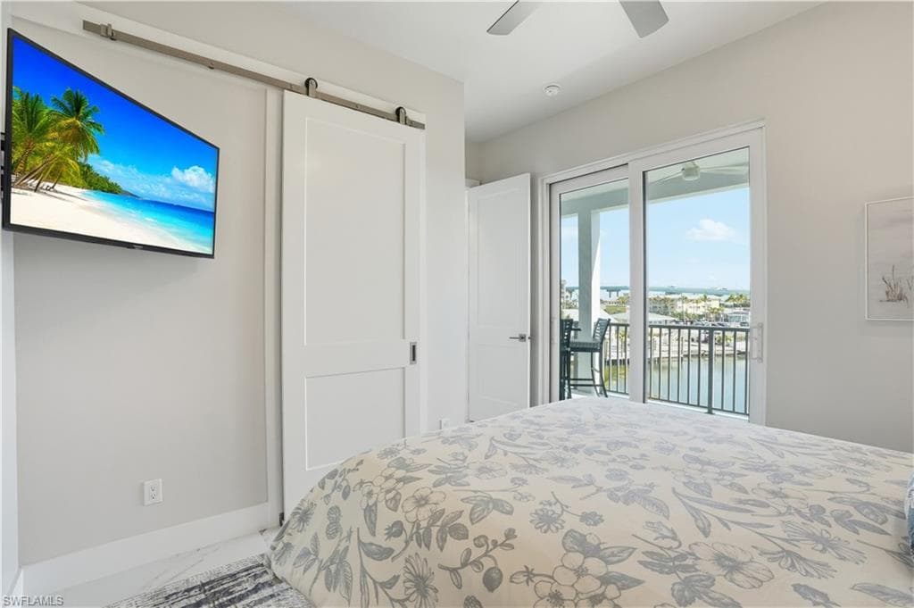 Bedroom featuring a water view, a barn door, access to outside, marble look tile flooring, and ceiling fan - Virtually Edited Image