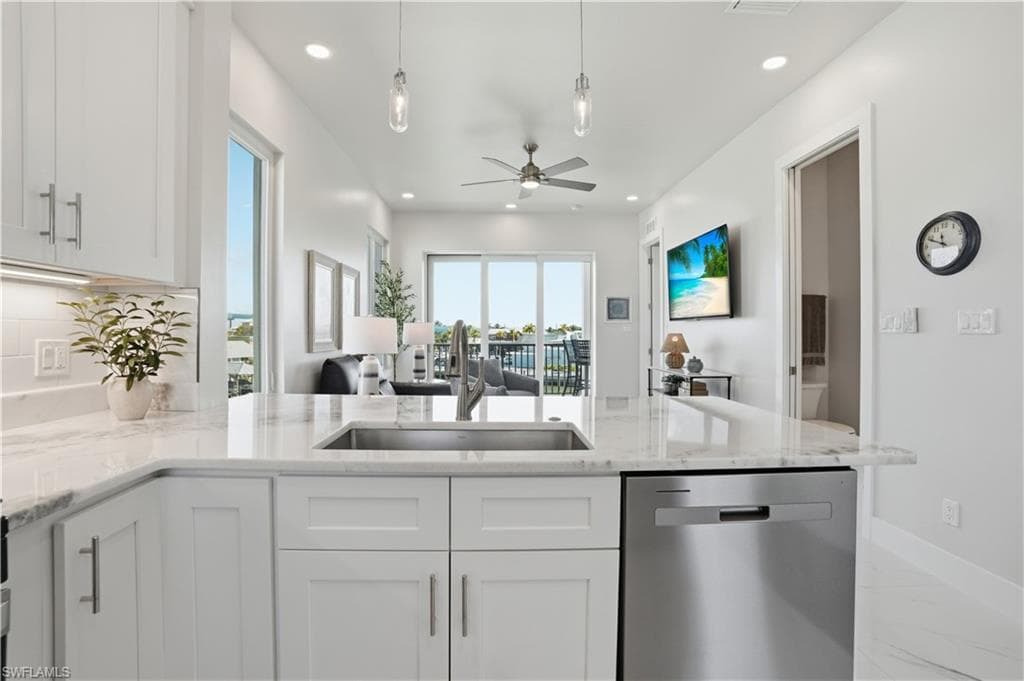 Kitchen with open floor plan, stainless steel dishwasher, light stone countertops, pendant lighting, and a peninsula - Virtually Edited Image