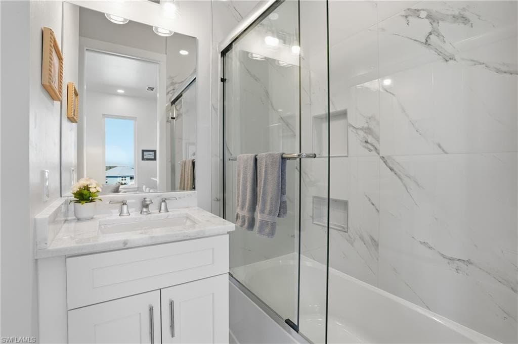 Ensuite bathroom featuring bath / shower combo with glass door and vanity - Virtually Edited Image
