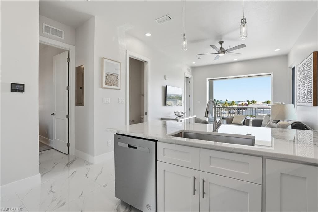 Kitchen featuring open floor plan, - Virtually Edited Imagestainless steel dishwasher, light stone countertops, white cabinets, and ceiling fan