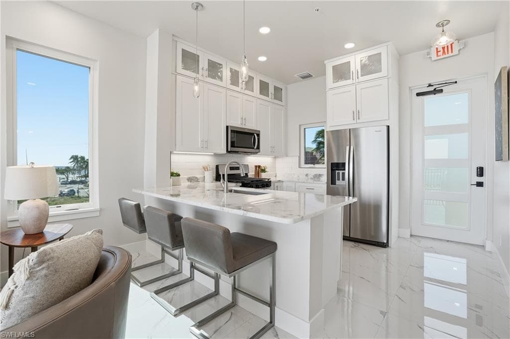 Kitchen with appliances with stainless steel finishes, white cabinets, tasteful backsplash, plenty of natural light, and recessed lighting - Virtually Edited Image