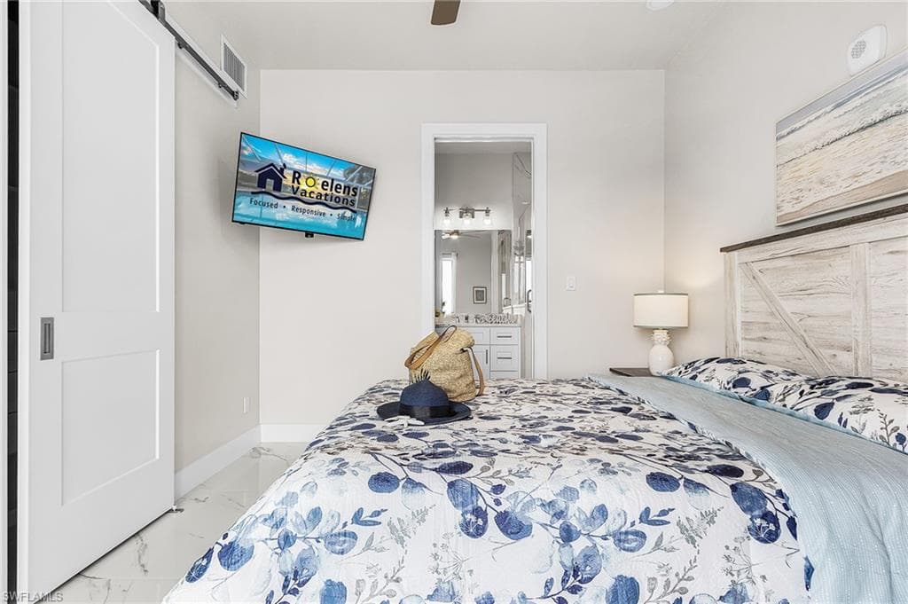 Bright room featuring white barn door, marble-look tile flooring, and a wall-mounted television - Virtually Edited Image
