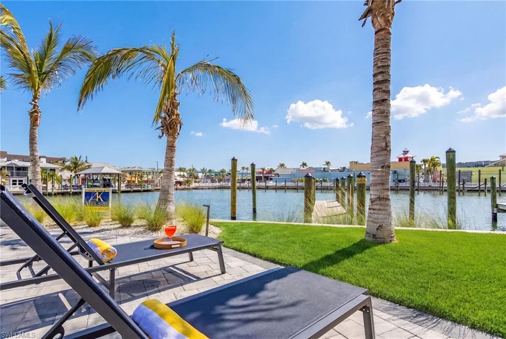 Waterfront patio with paver surfacing, featuring an adjacent lawn and tropical landscaping - Virtually Edited Image