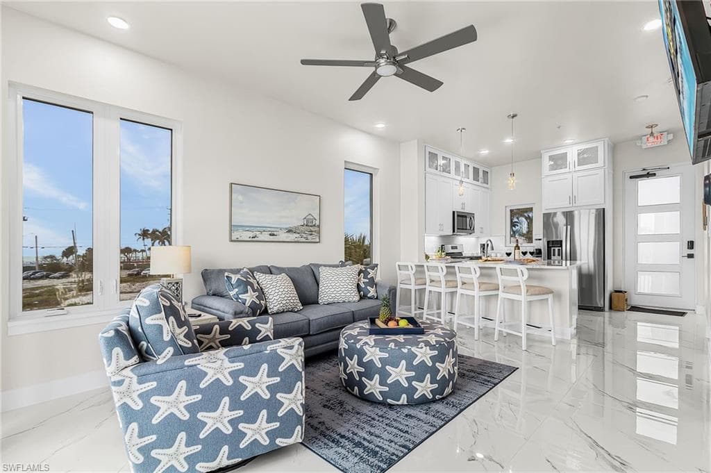 Open concept living area featuring high ceilings, recessed lighting, and large windows - Virtually Edited Image