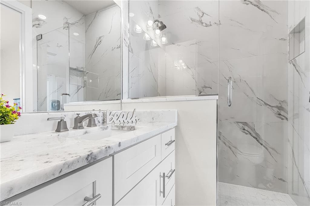 Bathroom vanity featuring a polished stone countertop, undermount sink, and brushed nickel fixtures - Virtually Edited Image