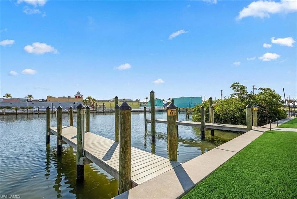 Waterfront property featuring a private boat dock, concrete pathway, manicured lawn, and mature foliage - Virtually Edited Image