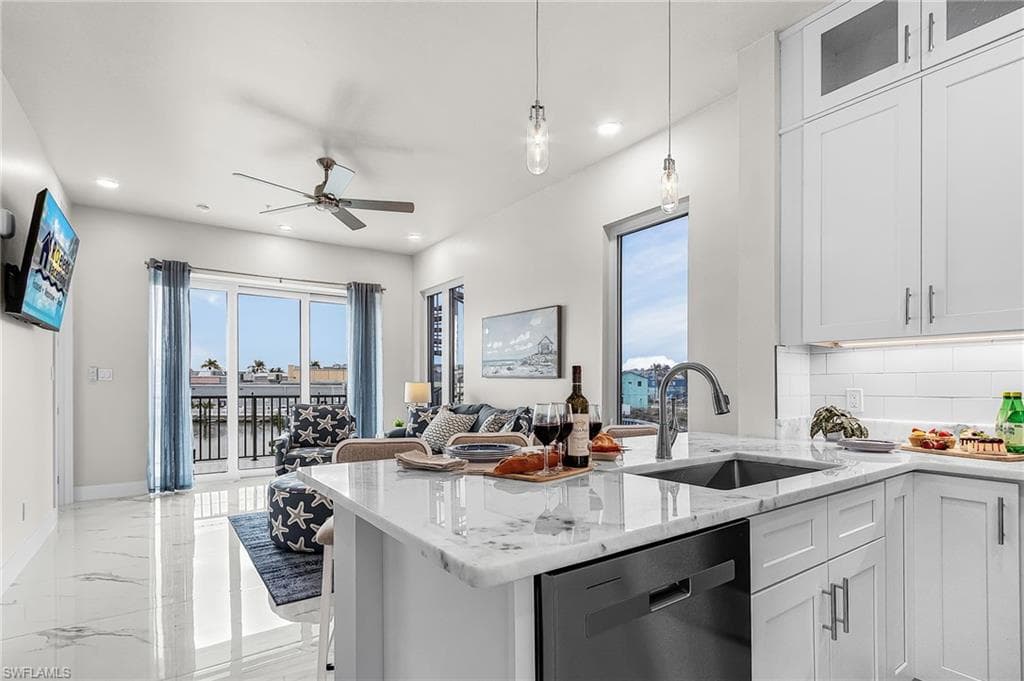 Contemporary kitchen featuring white cabinetry, stone countertops, a stainless steel sink, and an integrated dishwasher - Virtually Edited Image