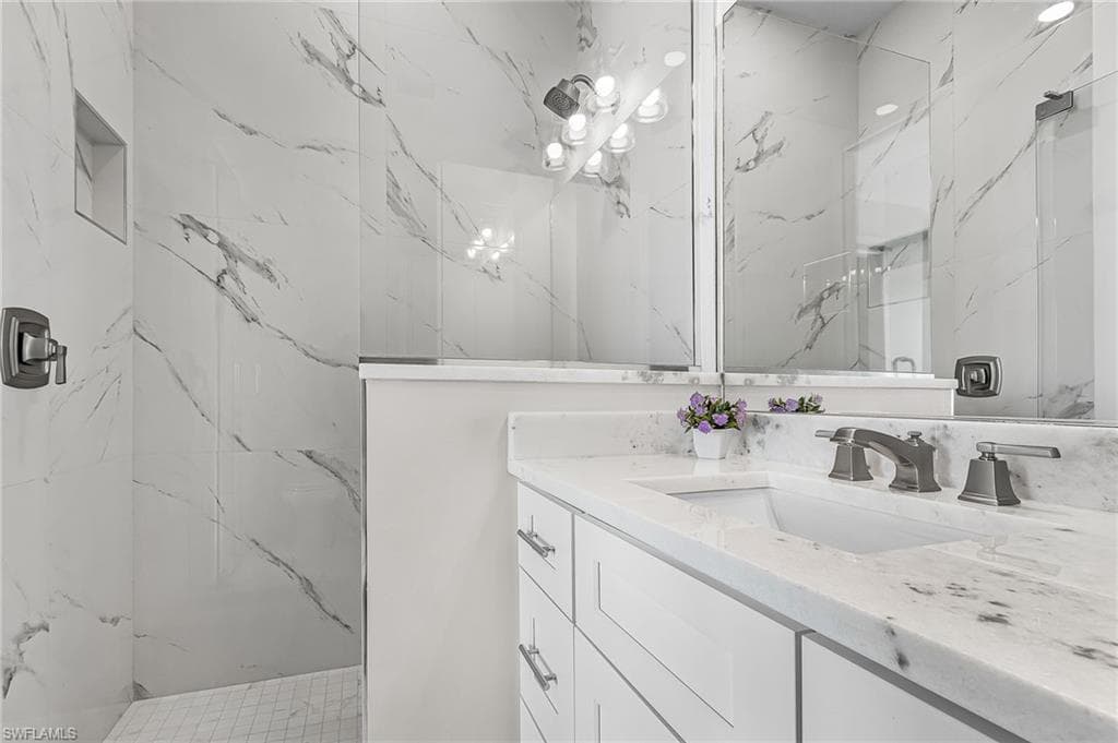 Bathroom featuring a white vanity with an undermount sink, a stone-finish countertop, and a dark bronze faucet - Virtually Edited Image