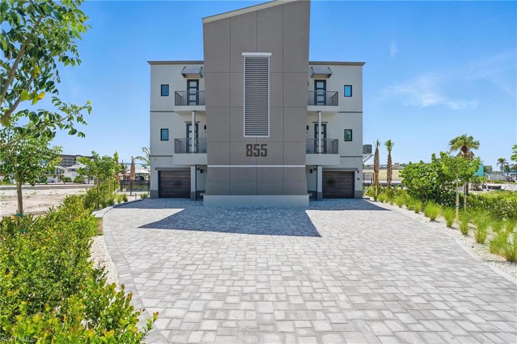 Front view of property featuring garage entry/exit and paver driveway - VIRTUALLY EDITED