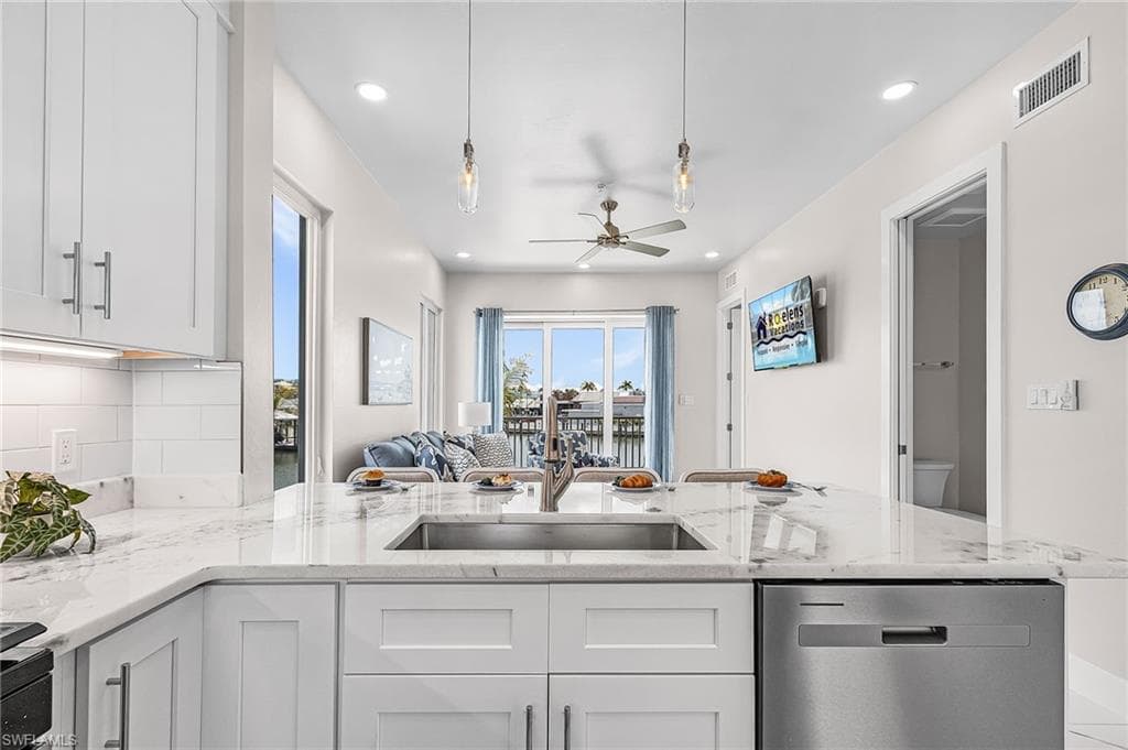 Expansive kitchen island featuring a stainless steel undermount sink, integrated dishwasher, and a light-toned countertop - Virtually Edited Image