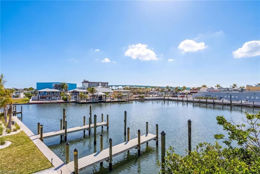 Waterfront property featuring multiple private dock slips, a manicured green space, and established shrubbery - Virtually Edited Image