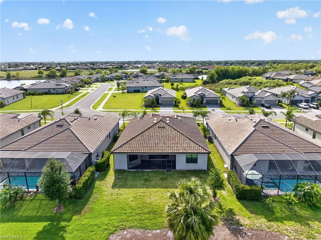 Rear exterior featuring a covered patio, expansive grassy lawn, and mature landscaping
