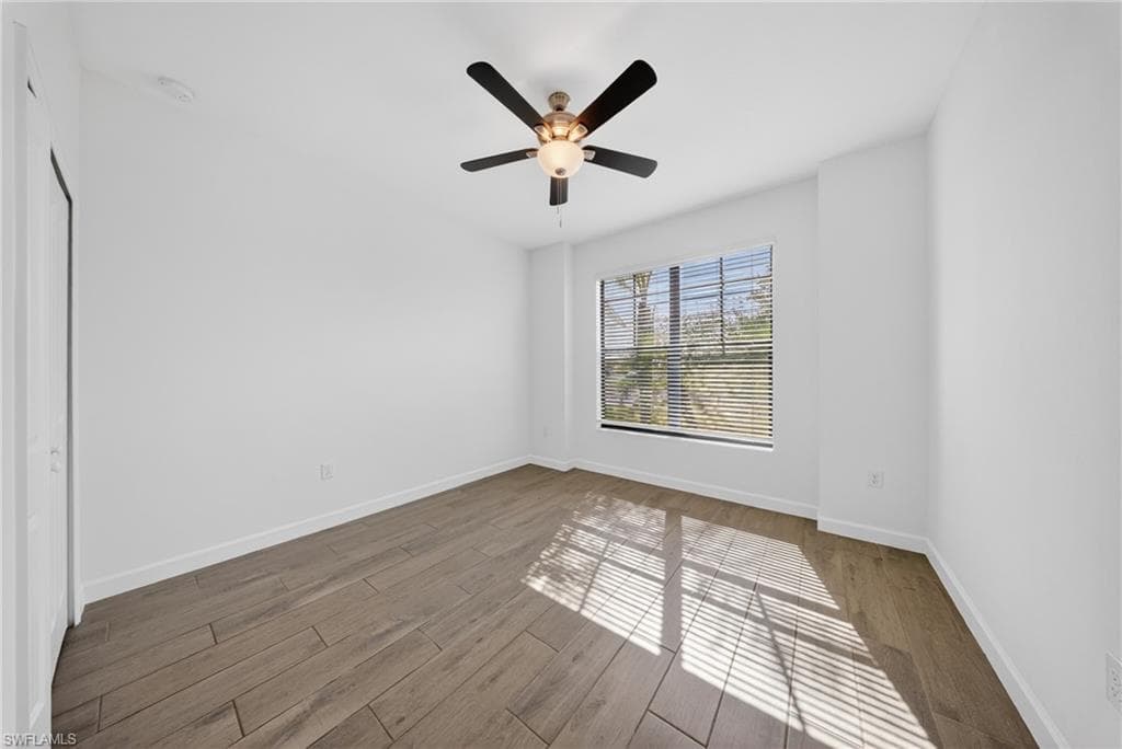 Expansive room featuring wood-finish flooring, a large window with horizontal blinds, a ceiling fan with integrated lighting, and recessed ceiling lighting