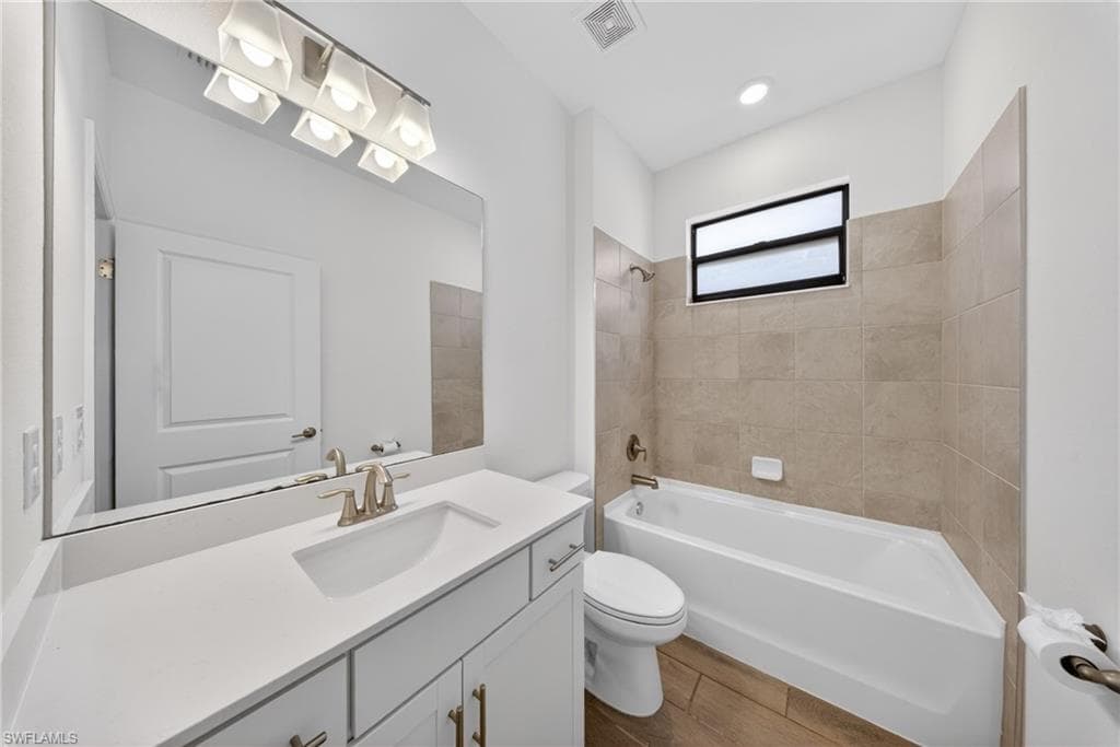 Bathroom featuring a white vanity with an integrated sink, brushed nickel faucet, large wall mirror, and modern overhead lighting