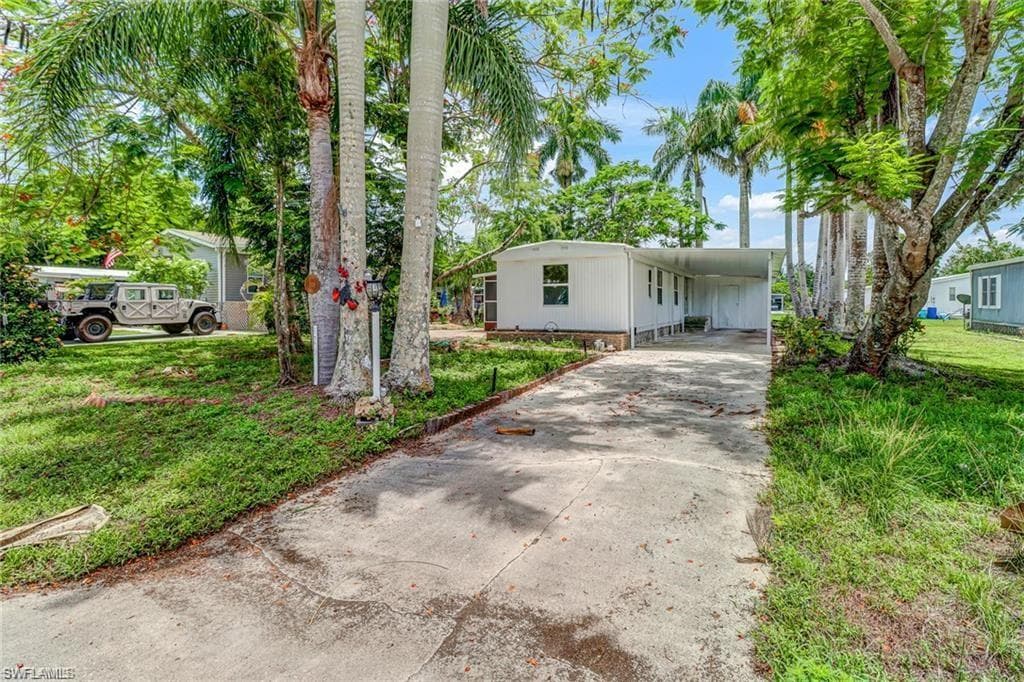 Manufactured / mobile home with driveway, an attached carport, and a front lawn