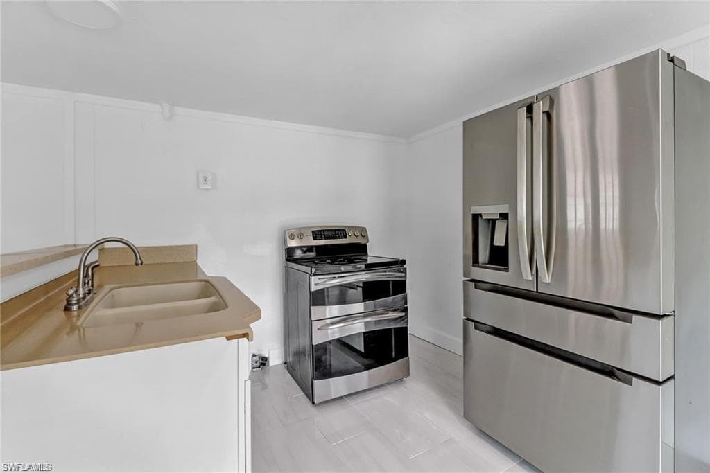 Kitchen featuring appliances with stainless steel finishes, white cabinets, and light countertops