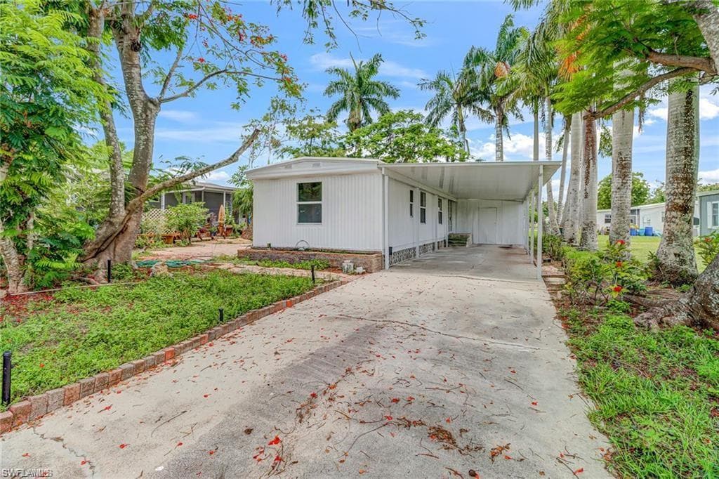 Manufactured / mobile home featuring concrete driveway and a carport
