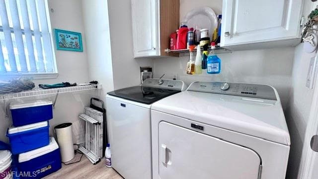 Dedicated laundry area featuring modern appliances, white cabinetry, a window with horizontal blinds, and wood-finish flooring
