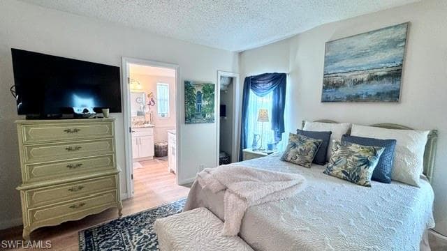 Bedroom with light wood-finish flooring and a private attached bath