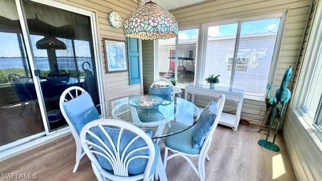 Sunroom featuring a Tiffany-style pendant light, wood-finish flooring, sliding glass door, and expansive windows