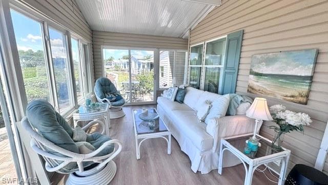 Enclosed sunroom featuring multiple large windows, light wood-finish flooring, and a sliding glass door