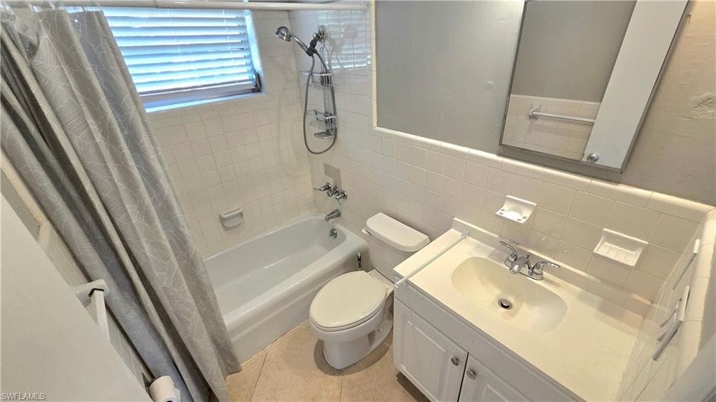 Bathroom #2 featuring a bathtub with shower fixture, white subway tile surround, white vanity with integrated sink, and an unframed mirror