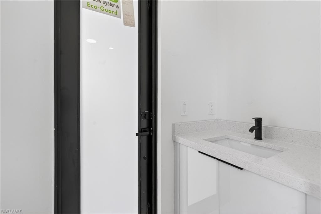 Bathroom vanity with a white rectangular undermount sink, speckled countertop, and a matte black single-handle faucet