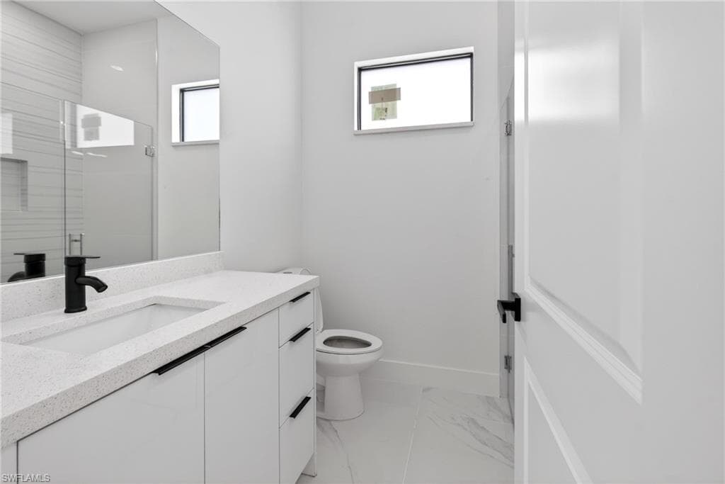 Bathroom featuring a white vanity with an integrated sink, black hardware, a matte black faucet, and a large wall mirror