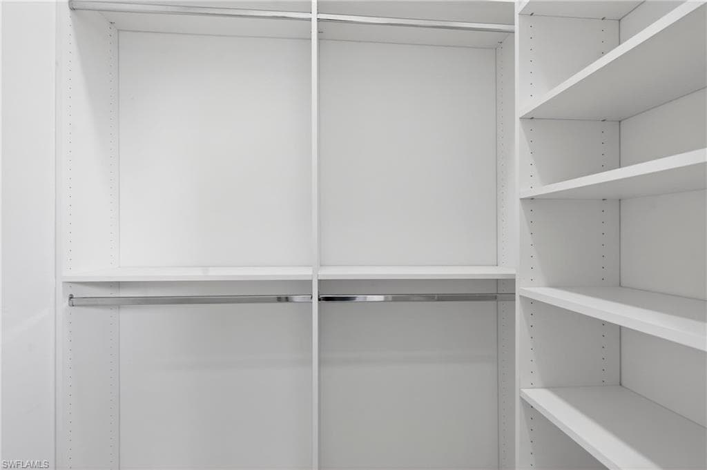 Custom closet system featuring white shelving, multiple hanging rods, and adjustable shelf heights